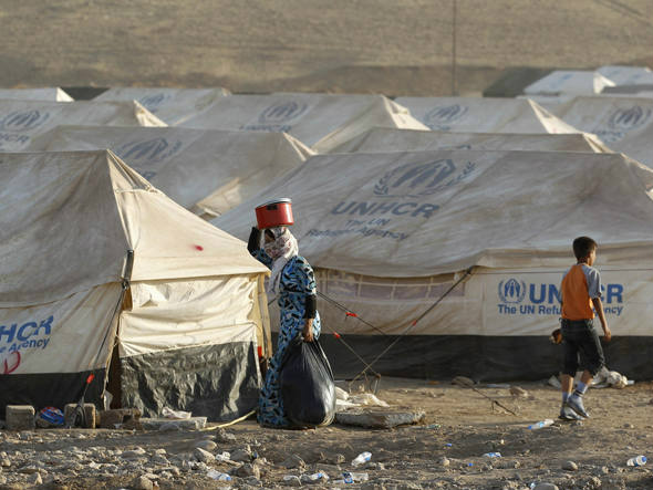 Refugiados sírios, em fuga da violência na Síria, caminham no campo de refugiados montados nos arredores da cidade de Arbil, no Iraque. (foto: Thaier al-Sudani/Reuters)