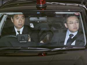 Makoto Hirata esconde o rosto no banco traseiro deum carro da polícia, enquanto de delegacia emTóquio. (Foto: Kyodo News / AP Photo)