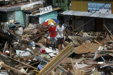 Moradores locais caminham entre casas devastadas pelo supertufão Haiyan, na região central das Filipinas. 