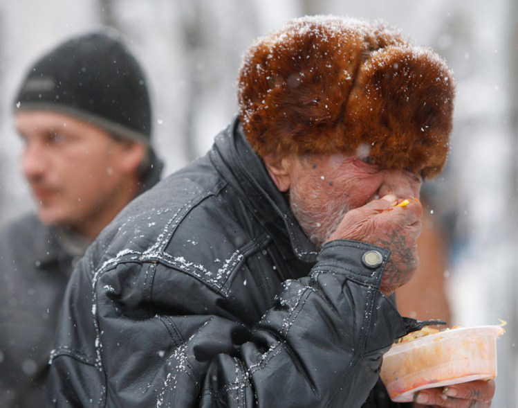 Um homem recebe uma refeição no meio do frio Eduard Korniyenko/Reuters 