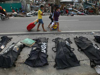 Pessoas cobrem os narizes ao passarem por corpos enfileirados em Tacloban