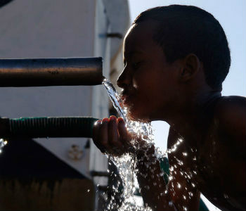 Menino se refresca de um dia quente em Omdurman, Sudão. Foto: World Bank/Arne Hoel.