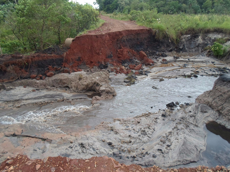 Estrada situada na Cabeçeira do Rio Panduí teve a vegetação arrancada e o “córrego” que passava sob a estrada se transformou em um Rio, abrindo uma grande cratera na localidade. / Foto: Decom