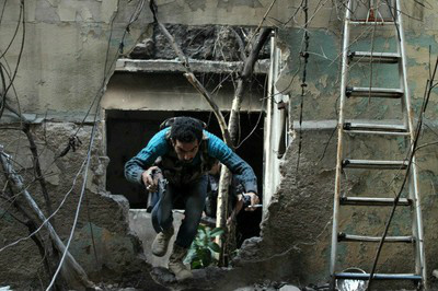 Em Aleppo, opositor a Assad passa por um buraco na parede para fugir dos tiros de atiradores de elite pró-regime, em 19 de novembro
