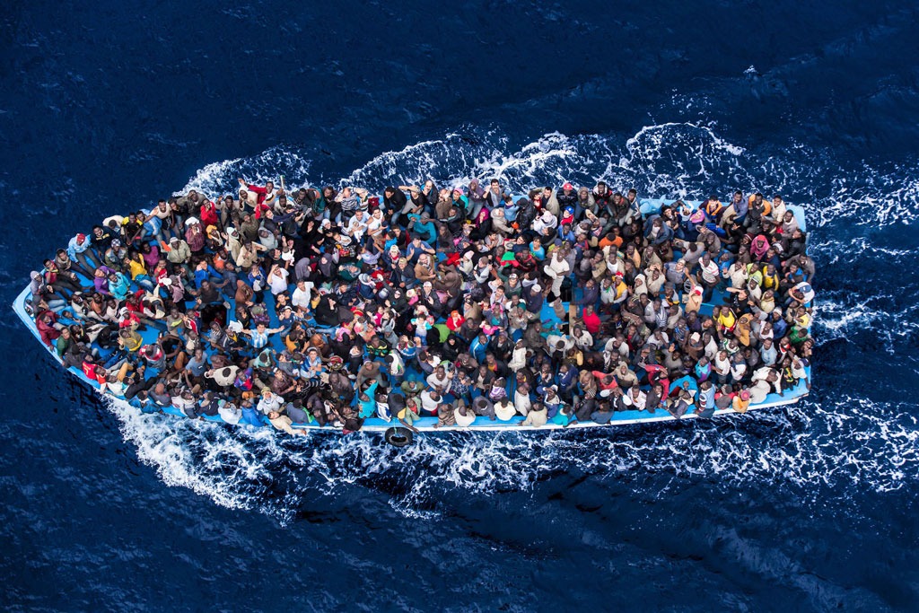 Centenas de refugiados e migrantes a bordo de um barco de pesca momentos antes de serem resgatados pela Marinha italiana, como parte de sua operação Mare Nostrum, de junho de 2014. Foto: Marinha italiana/Massimo Sestini