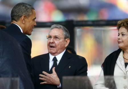 Presidente dos Estados Unidos, Barack Obama, cumprimenta o presidente de Cuba, Raúl Castro, observado pela presidente Dilma Rousseff, durante funeral do ex-presidente da África do Sul Nelson Mandela, em Johanesburgo.