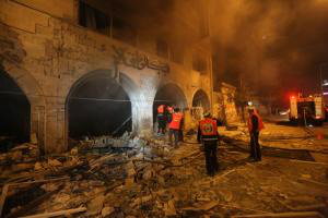Palestinos tentam apagar um incêndio em uma agência do Banco Nacional Islâmico, após um ataque aéreo de Israel(Yasser Qudin / Télam)
