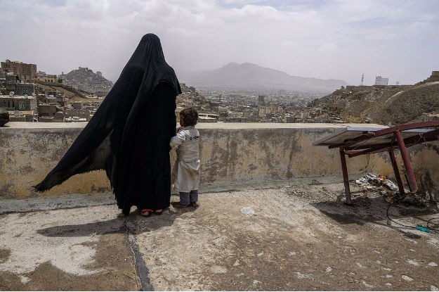 Uma mulher deslocada internamente e sua filha olham a cidade de Sanaa, no Iêmen, a partir do telhado do prédio onde está abrigada. Foto: Giles Clarke/ Ocha.