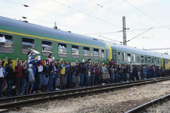 Migrantes e policiais durante distribuição de alimentos na Estação Ferroviária de Bicske, na Hungria - EPA/Herbert P. Oczeret/Agência Lusa/Direitos Reservados