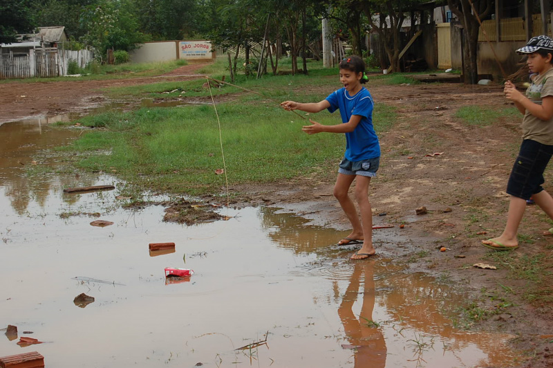 Crianças brincam de pescaria em alagado após chuva em Amambai