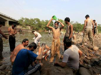 Homens se refrescam em um córrego na cidade de Islamabad, no Paquistão, no dia 23 de junho de 2015. Reuters