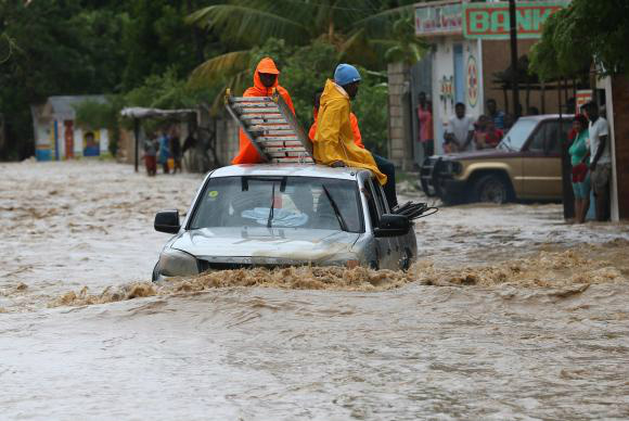 Doações para vítimas do furacão no Haiti são insuficientes Um grupo de pessoas tenta cruzar uma via alagada in Leogane, no Haiti, após a passagem do Furacão Matthew -Orlando Barria/EPA/Agência Lusa/direitos reservados