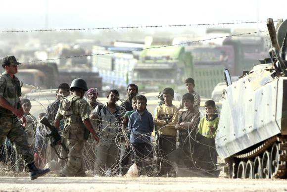 Refugiados sírios aguardam na fronteira com a Turquia para fugir dos ataques do Estado IslâmicoULS