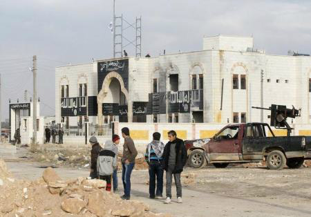Pessoas em frente ao que era anteriormente uma base utilizada por militantes do Estado Islâmico do Iraque e do Levante (ISIL, na sigla em inglês) na cidade de al-Dana, em Idlib. 