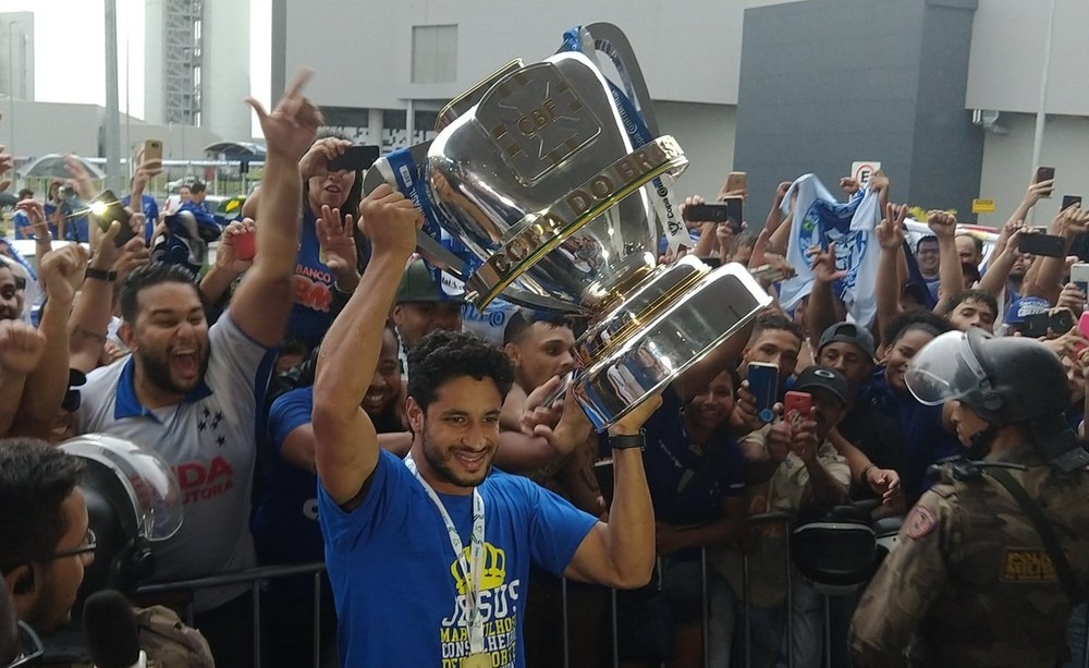 Léo ergueu o troféu na chegada ao aeroporto — Foto: Guilherme Macedo