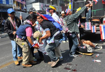 Manifestantes contrários ao governo ajudam a carregar homem ferido por uma explosão durante um protesto em Bangcoc. 