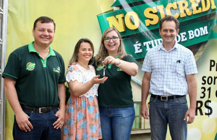 Associada do Sicredi em Deodápolis recebe carro 0 km Associada Sônia Regina recebe a chave do veículo das mãos do Vice-presidente, do Diretor Executivo e da Gerente do Sicredi em Deodápolis. Foto: Cristiane Santos