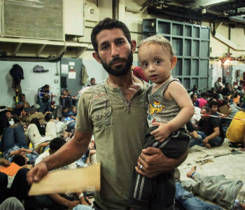 Homem sírio com seu filho de um ano de idade que foram resgatados no Mediterrâneo. Foto: Acnur/A. D’Amato