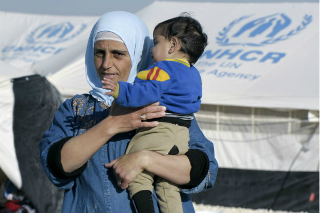 Mulher segura criança síria em campo de refugiados. UN Photo/Mark Garten