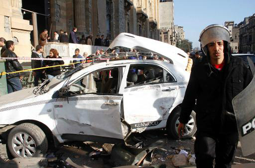 Policial egípcio ao lado de carro atingido pela explosão de um carro-bomba em frente ao quartel-general da polícia, no Cairo (AFP, KHALED KAMEL)