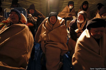 Japonesas se aquecem em um acampamento da Cruz Vemelha Internacional.