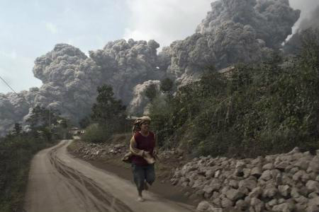 Aldeão corre após o vulcão Monte Sinabung entrar em erupção neste sábado, na ilha ocidental de Sumatra, na Indonésia.