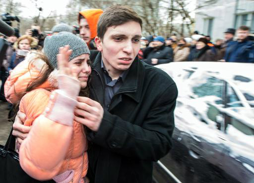 Estudante deixa a escola acompanhada por um parente (AFP, Dmitry Serebryakov)