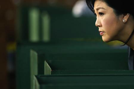 Primeira-ministra da Tailândia, Yingluck Shinawatra, vislumbra à frente a partir de uma urna, enquanto vota nas eleições antecipadas, em Bangcoc. 