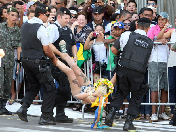 Ativista do grupo feminista Femen tira a blusa e exibe cartaz de protesto ao invadir a pista onde acontecem os desfiles de 7 de Setembro na Esplanada dos Ministérios, em Brasília. Duas ativistas foram presas. (Foto: André Dusek/AE)