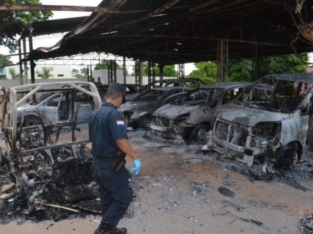 Quadrilha que explodiu casas e loja encurralou 12 policiais em delegacia Policial observa carros destruídos em loja da família Alderete (Foto: ABC Color)
