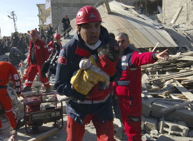 Oficial de resgate retira uma menina encontrada em meio aos escombros ainda com vida na segunda (24) em Ercis, perto da cidade de Van (Foto: Reuters)