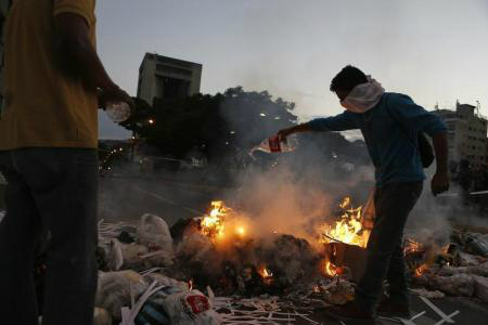 Manifestantes da oposição próximos a barricada, em Caracas. 