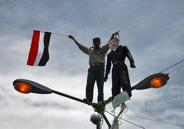 Manifestante pede saída de Saleh do poder com boneco com foto do rosto do presidente, neste sábado (23), na capital o Iêmen. (Foto: AFP)