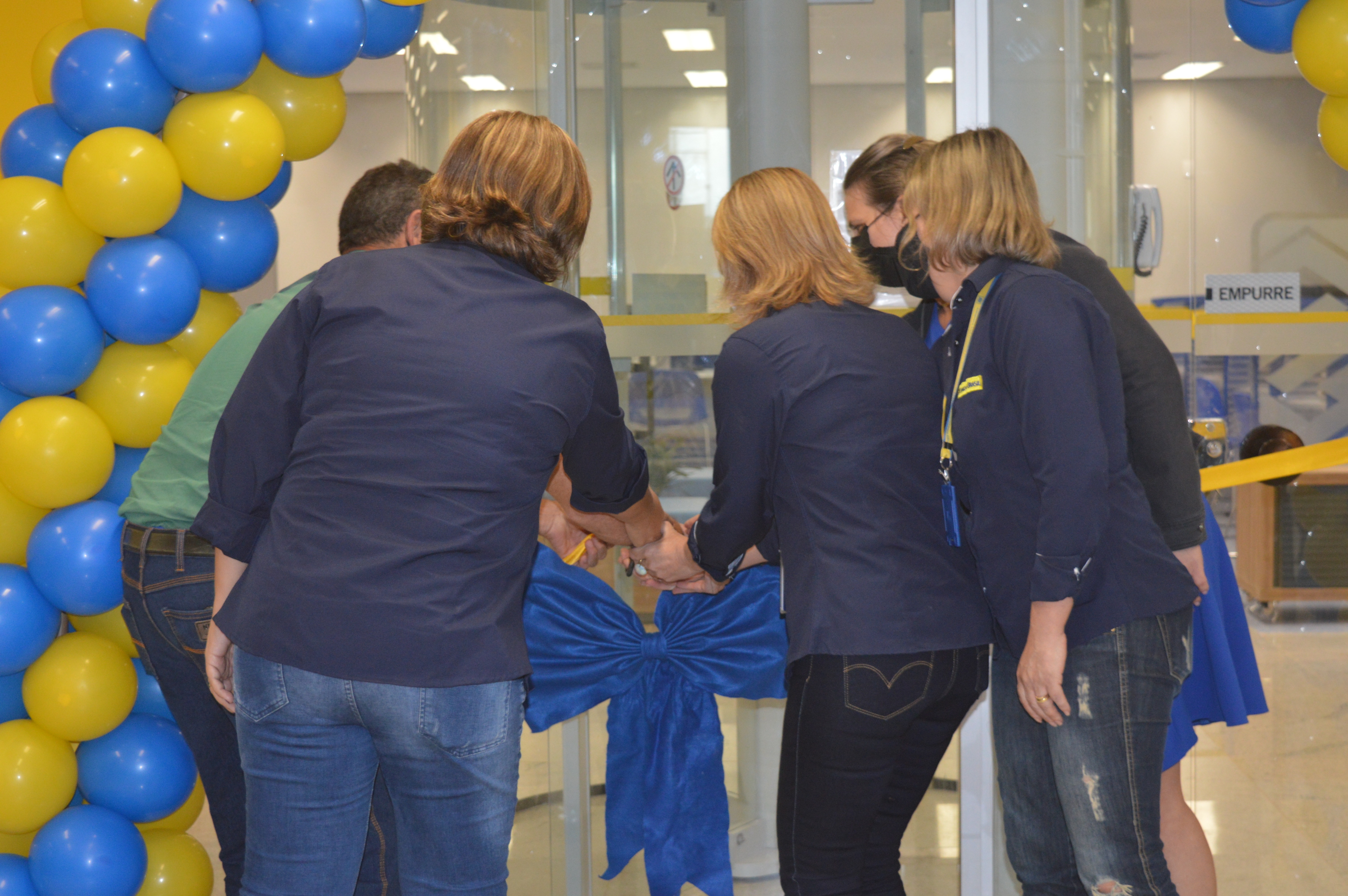 A gerente geral da agência do Banco do Brasil, Rejane Culau, junto dos seus funcionários mais antigos cortando a fita de inauguração. / Foto: Moreira Produções