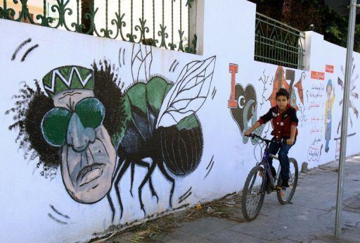 Criança líbia passa por desenho do ex-ditador Muamar Kadhafi em muro de Trípoli (AFP/Arquivo, Mahmud Turkia)