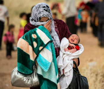 Mulher síria cruza a fronteira com a Jordânia com seu bebê. Foto: Acnur/S. Rich