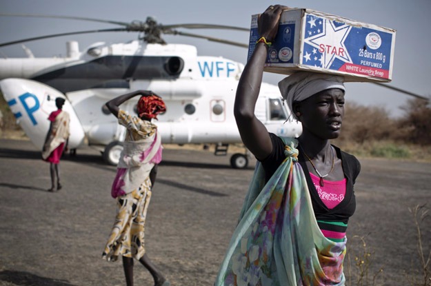 Mulher carrega kit de emergência alimentar entregue por um helicóptero do Programa Mundial de Alimentos no Sudão do Sul. Foto: Unicef/Holt