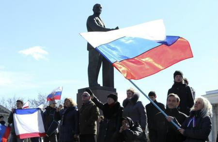 Participantes de uma manifestação pró-Rússia agitam bandeiras russas na frente da estátua de Lenin, em Simferopol. 