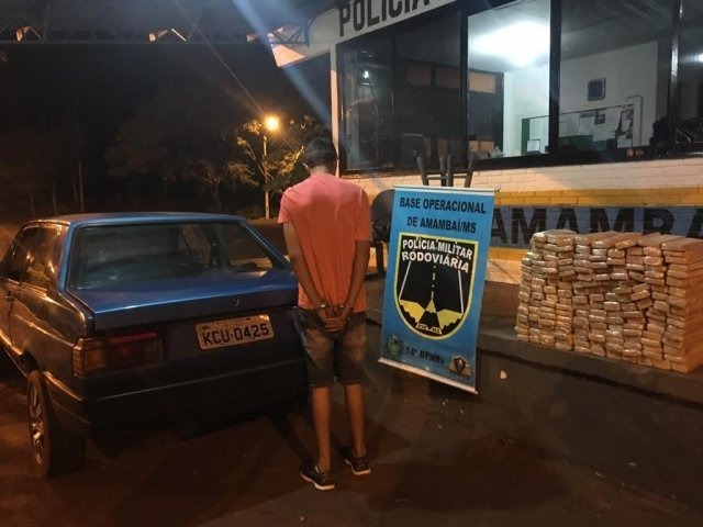 Jovem é preso com 112 quilos de maconha em lataria de carro, em Amambai Traficante ao lado do veículo e os tabletes de maconha que transportava. (Foto: Divulgação/PMR)