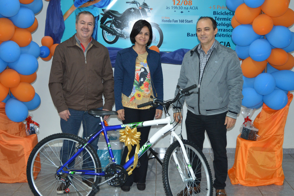 Prêmios da campanha Pai Premiado da Acia já foram entregues E/D: presidente da Acia, Clemente Martins Júnior, a ganhadora da bicicleta, Rosana Colman e o vice-presidente da Acia, Clésio Ribeiro / Foto: Moreira Produções