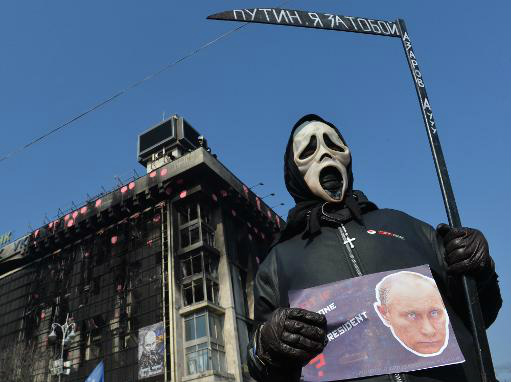 Um homem vestido de morte exibe um cartaz com a imagem do presidente russo, Vladimir Putin, em Kiev no dia 24 de março de 2014 (AFP, Sergei Supinsky)