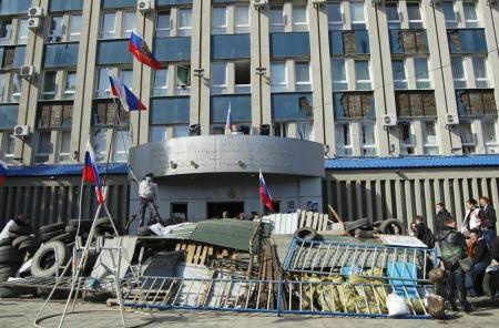 Manifestantes pró-Rússia se aglomeram em uma barricada montada em frente ao edifício do serviço de segurança estatal SBU, em Luhansk, leste da Ucrânia. 